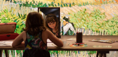 Een meisje tekent in de Experience haar eigen zelfportret met behulp van een spiegel.