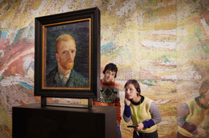 Een jongen en een meisje kijken naar de achterkant van een zelfportret van Vincent van Gogh, terwijl ze luisteren naar de audiotour, foto Maaike Koning